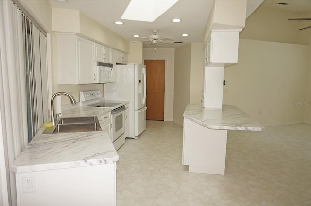 kitchen with white appliances, sink, white cabinetry, a skylight, and kitchen peninsula