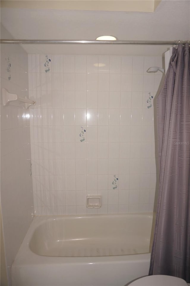 bathroom with shower / bath combination with curtain and toilet