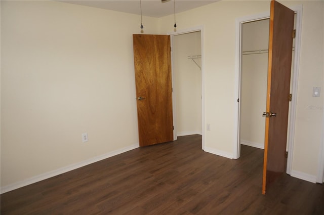 unfurnished bedroom with dark wood-type flooring and two closets