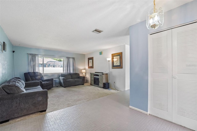 carpeted living room featuring a textured ceiling and a chandelier