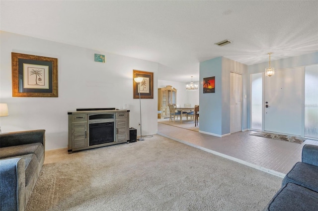 living room featuring a textured ceiling, an inviting chandelier, and carpet flooring