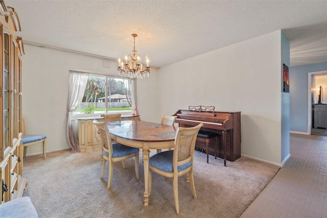 dining room with light colored carpet, a notable chandelier, and a textured ceiling