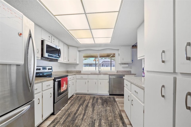 kitchen featuring hardwood / wood-style floors, stainless steel appliances, white cabinetry, and sink