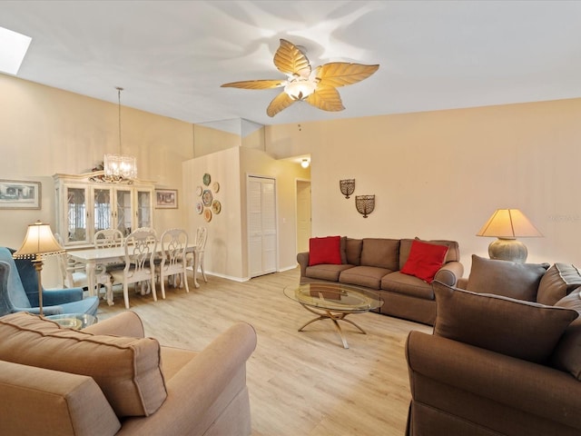 living room with light wood-type flooring, ceiling fan with notable chandelier, and a skylight