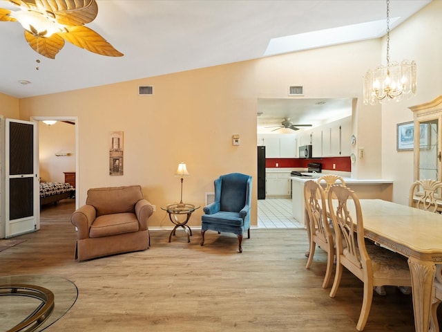 interior space with ceiling fan with notable chandelier and lofted ceiling with skylight