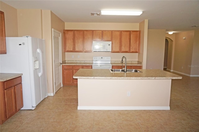 kitchen featuring white appliances, a center island with sink, light tile patterned floors, and sink