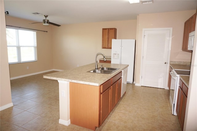 kitchen featuring white appliances, an island with sink, ceiling fan, light tile patterned floors, and sink