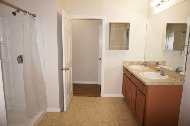 bathroom featuring a shower with shower curtain, dual bowl vanity, and tile patterned floors