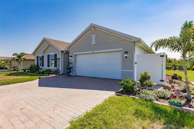 ranch-style house featuring stucco siding, an attached garage, a gate, decorative driveway, and a front yard