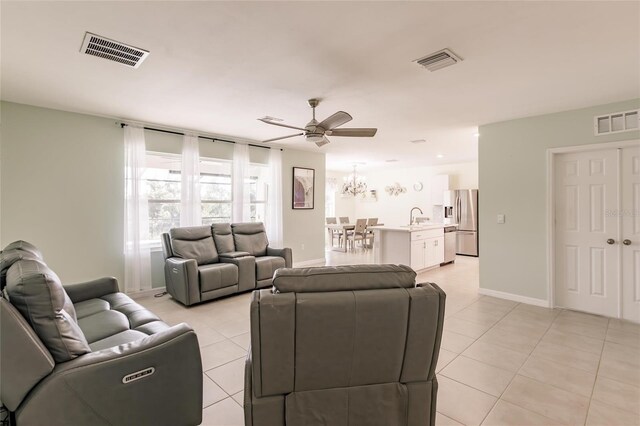 tiled living room with sink and ceiling fan with notable chandelier