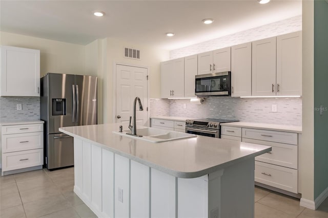 kitchen featuring light tile patterned floors, appliances with stainless steel finishes, tasteful backsplash, and a center island with sink