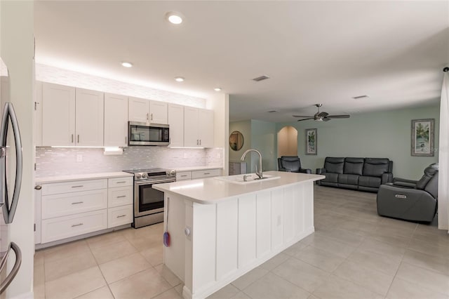 kitchen featuring sink, stainless steel appliances, light tile patterned flooring, and white cabinetry