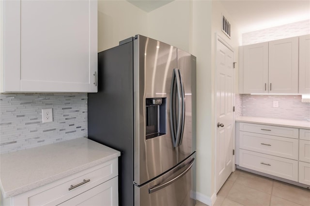 kitchen featuring white cabinets, light tile patterned floors, backsplash, and stainless steel refrigerator with ice dispenser