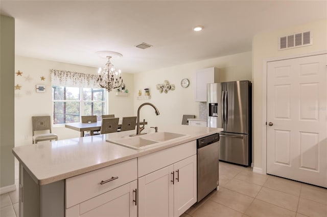 kitchen with appliances with stainless steel finishes, white cabinetry, sink, an island with sink, and pendant lighting