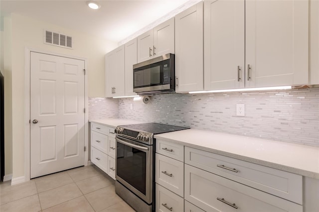 kitchen featuring white cabinetry, appliances with stainless steel finishes, light tile patterned floors, and decorative backsplash