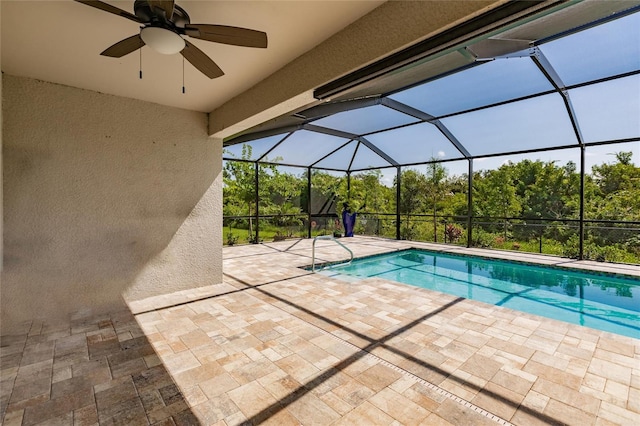 view of swimming pool with ceiling fan, glass enclosure, and a patio area