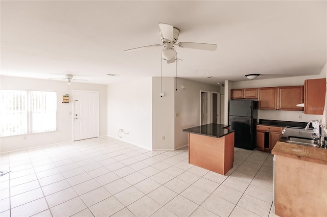 kitchen featuring sink, black fridge, light tile patterned floors, and ceiling fan