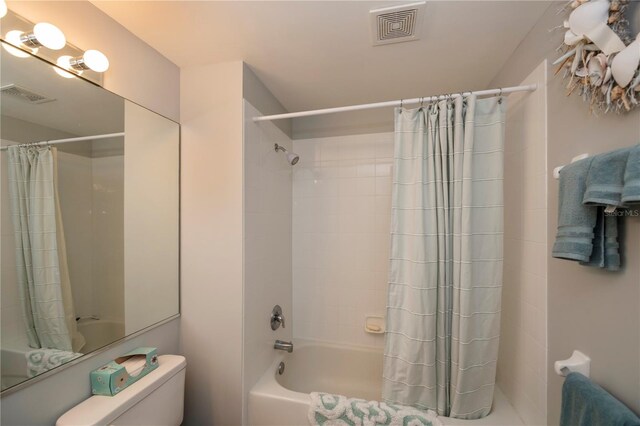 bathroom featuring shower / bathtub combination with curtain and toilet