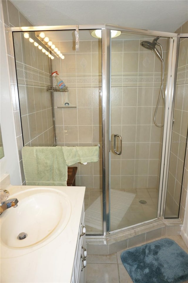 bathroom featuring tile patterned flooring, a shower with door, and vanity