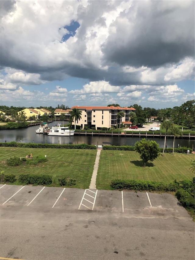 view of parking / parking lot with a yard and a water view