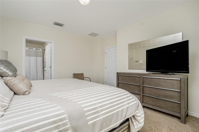 bedroom with ensuite bath and light carpet