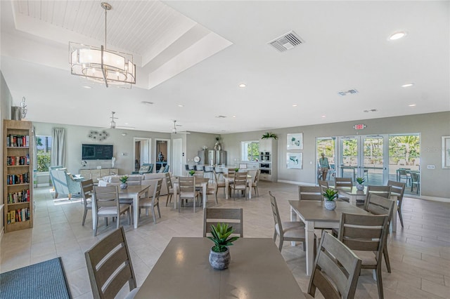 tiled dining room with a tray ceiling, a chandelier, and french doors