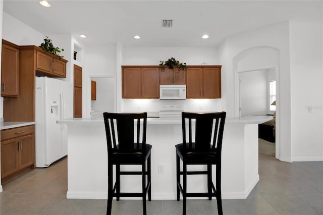 kitchen featuring light tile patterned floors, white appliances, and a kitchen island