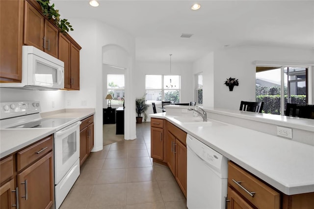 kitchen with light tile patterned floors, sink, white appliances, and decorative light fixtures