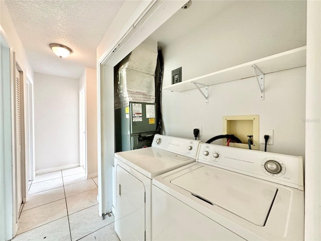 laundry area with a textured ceiling, light tile patterned floors, and washing machine and clothes dryer