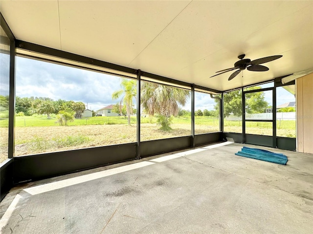 unfurnished sunroom featuring ceiling fan and a wealth of natural light