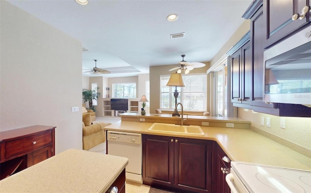 kitchen with a tray ceiling, ceiling fan, sink, and white dishwasher