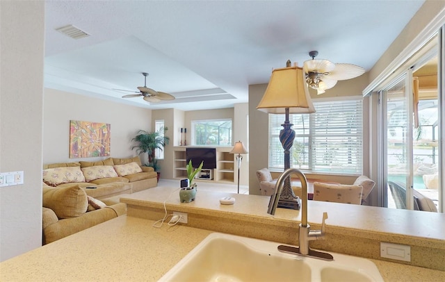 kitchen with ceiling fan, sink, and a tray ceiling