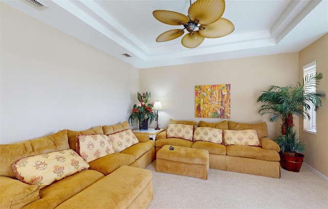 living room featuring ceiling fan, carpet flooring, a tray ceiling, and a healthy amount of sunlight