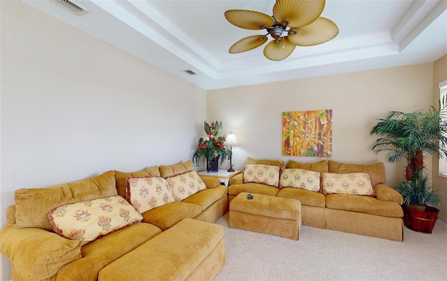 carpeted living room with ceiling fan and a tray ceiling