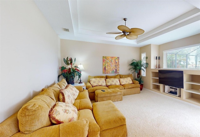 living room with ceiling fan, carpet flooring, and a tray ceiling