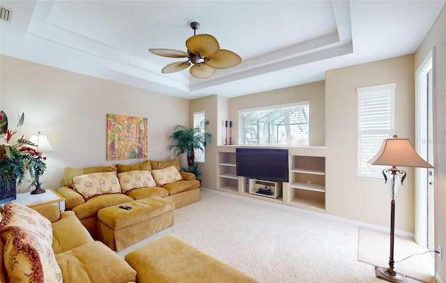 carpeted living room featuring ceiling fan and a raised ceiling