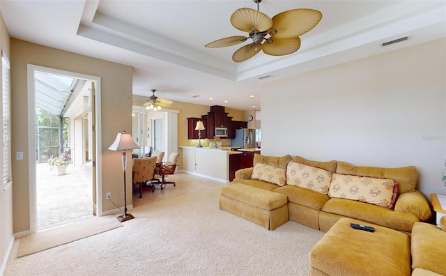 carpeted living room featuring ceiling fan and a raised ceiling