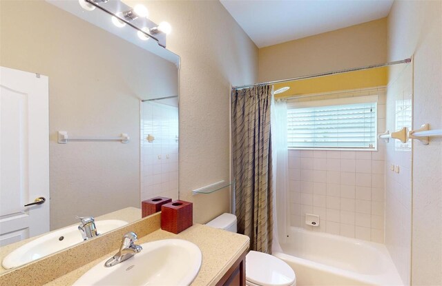 full bathroom featuring vanity, shower / bathtub combination with curtain, and toilet