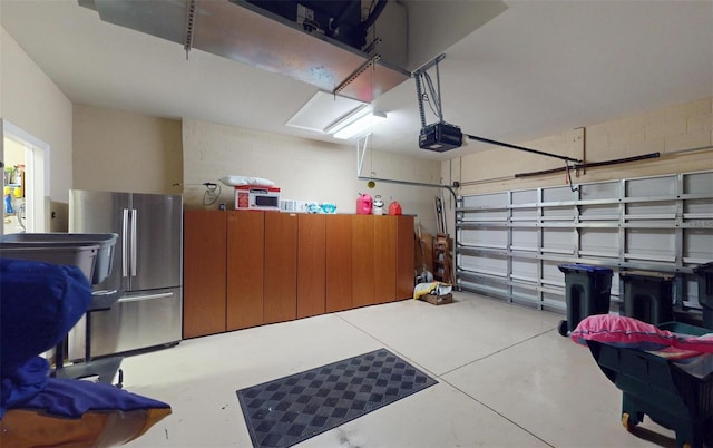 garage featuring stainless steel refrigerator and a garage door opener