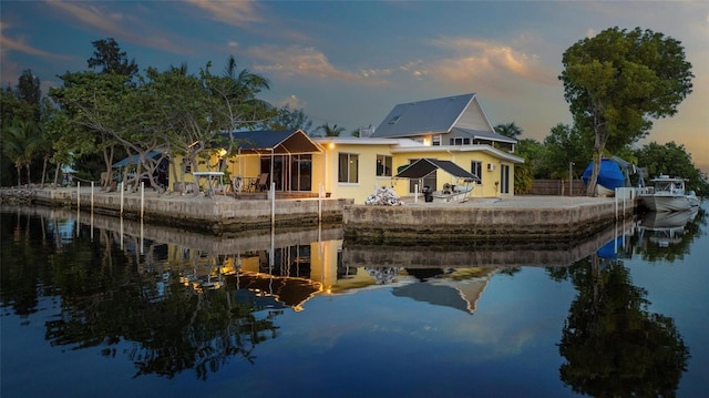 back house at dusk featuring a patio area and a water view