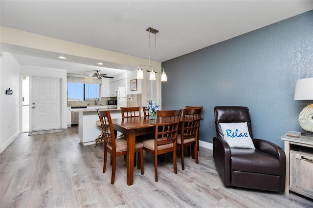 dining room with light hardwood / wood-style floors, ceiling fan, and sink