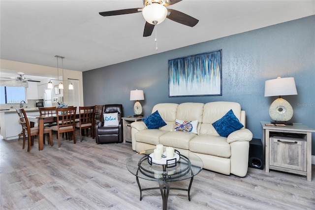 living room featuring ceiling fan and light hardwood / wood-style flooring