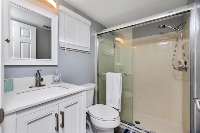 bathroom featuring vanity, toilet, and a shower with door