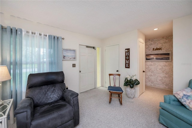 carpeted living area featuring wallpapered walls and a textured ceiling