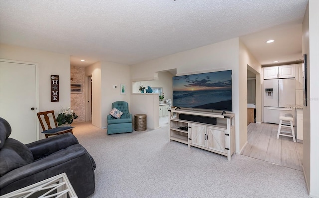 living area with a textured ceiling, recessed lighting, and light colored carpet