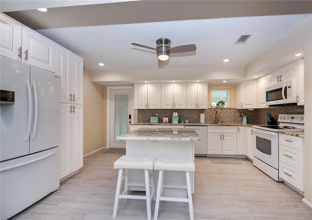 kitchen featuring white appliances, a sink, visible vents, white cabinetry, and backsplash