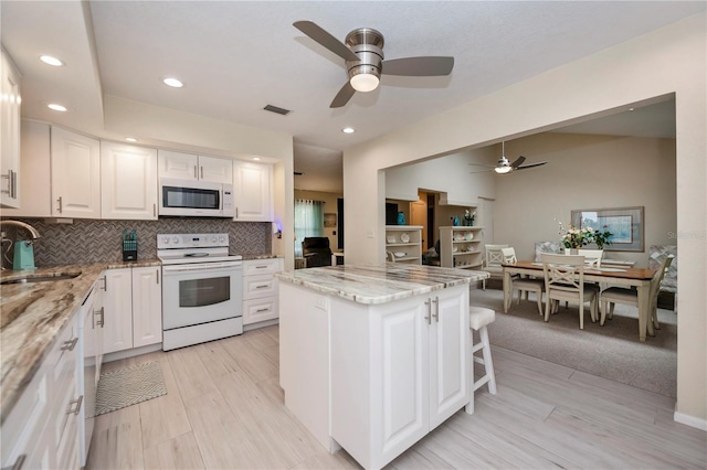 kitchen featuring white appliances, a sink, visible vents, white cabinetry, and backsplash