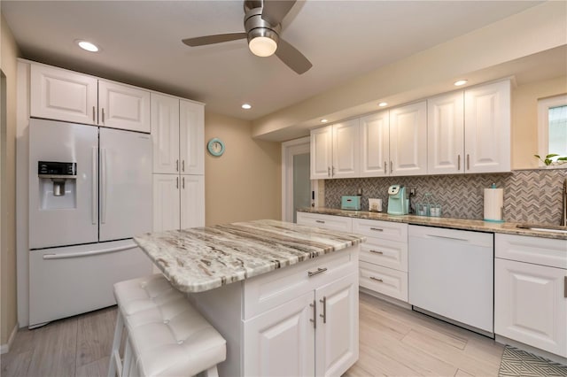 kitchen with white dishwasher, fridge with ice dispenser, white cabinets, and a center island