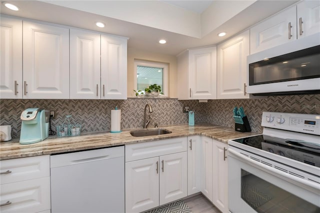 kitchen featuring white appliances, a sink, and white cabinetry