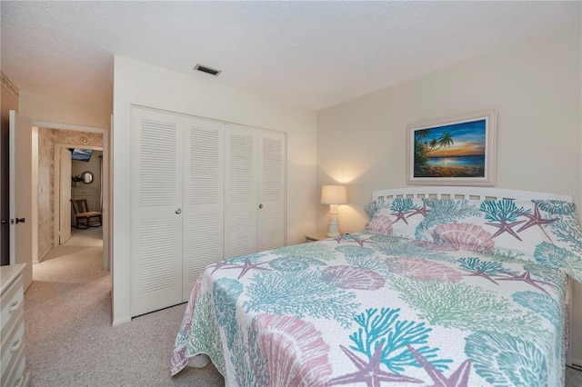 bedroom with light colored carpet, a closet, visible vents, and a textured ceiling